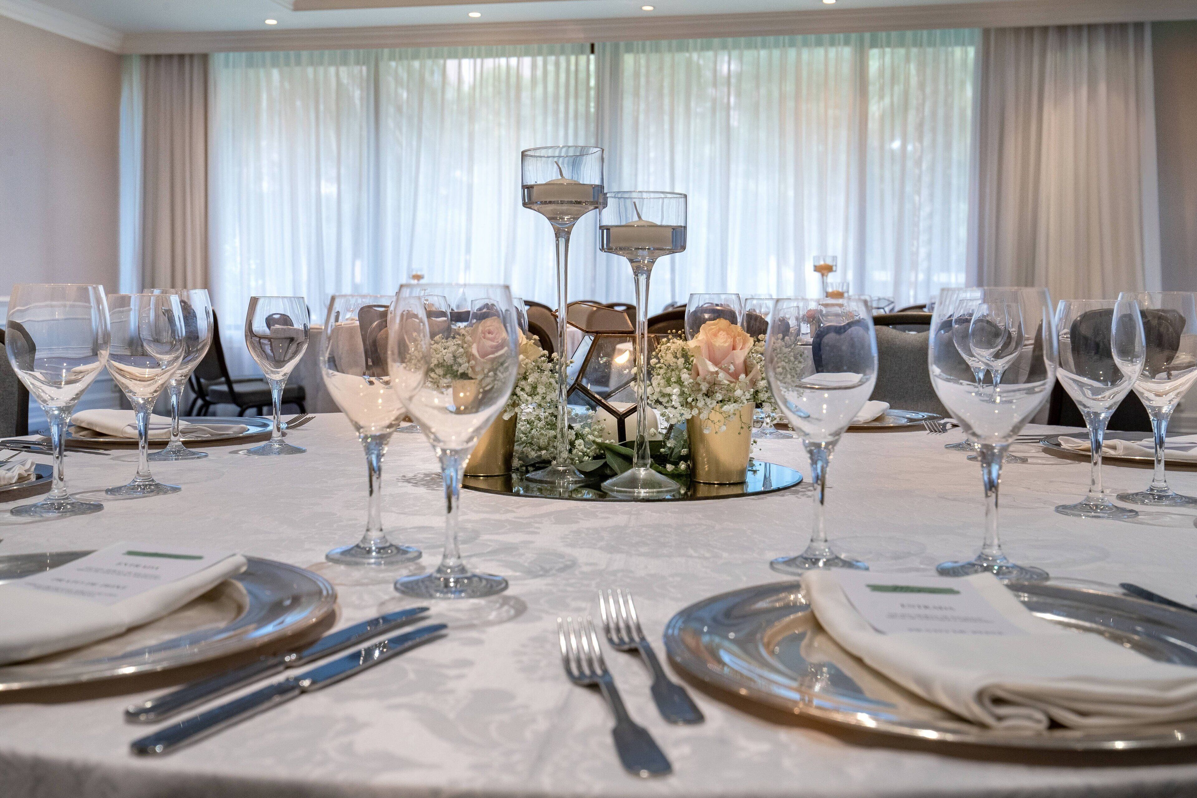 Une table à manger dressée pour un repas formel, avec de nombreux verres à vin, des assiettes et des couverts.