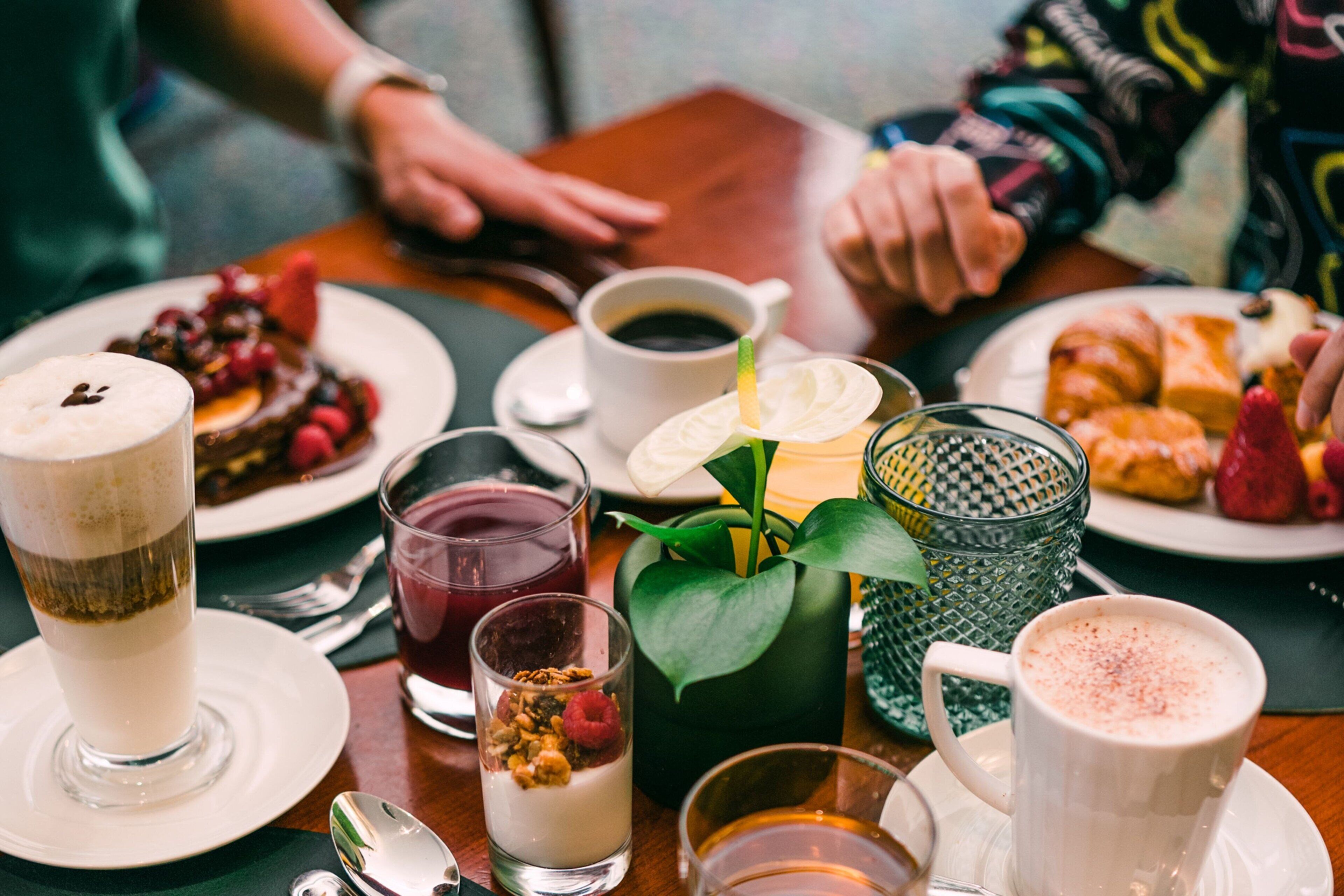 A dining table with various food items and drinks, including a plate of pastries, a glass of milk, and a cup of coffee.