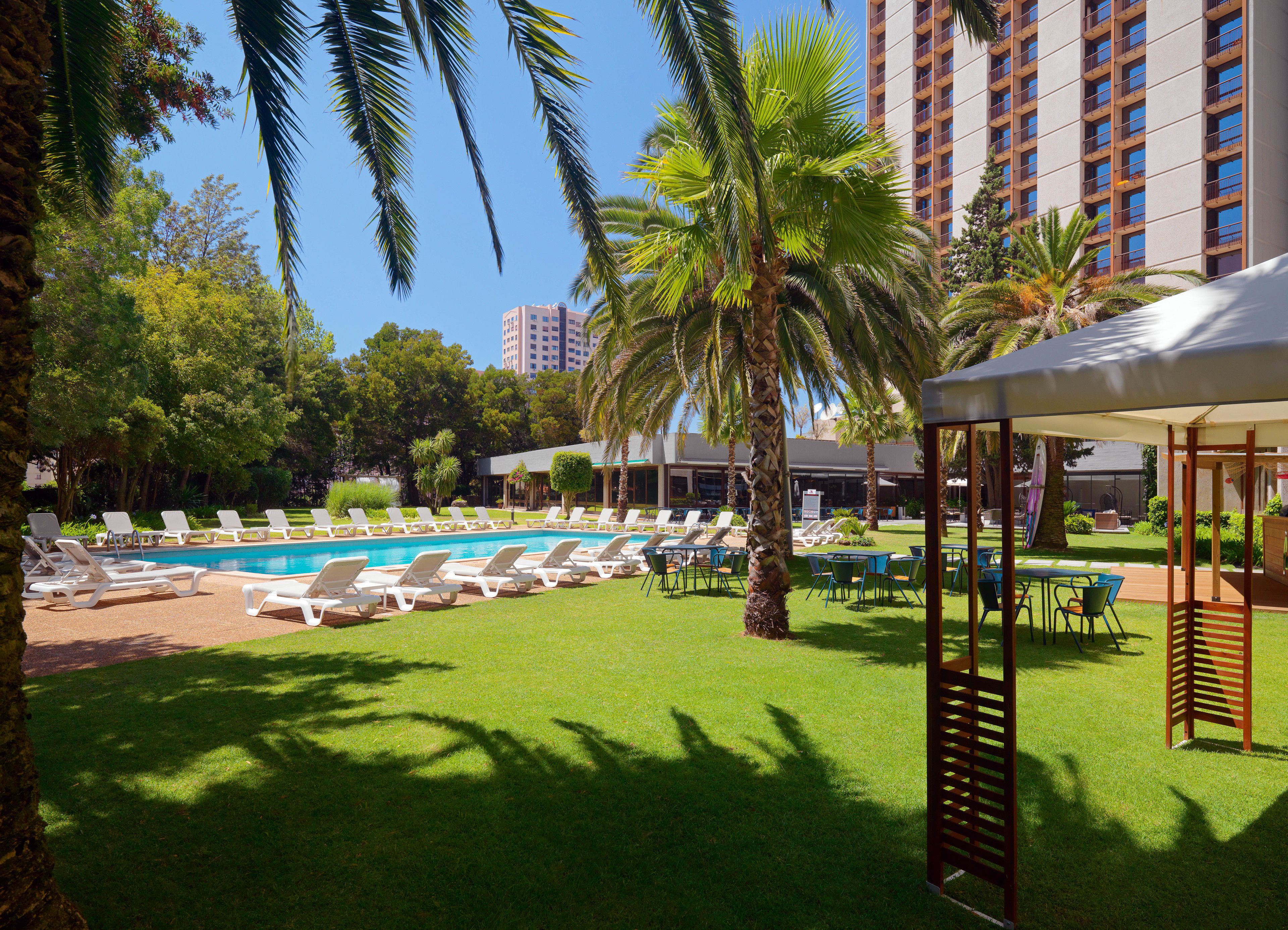 A pool area with lounge chairs and a gazebo.