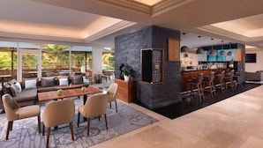 Amplia sala de estar con un bar moderno, asientos cómodos y ventanas grandes que ofrecen vistas al exterior.