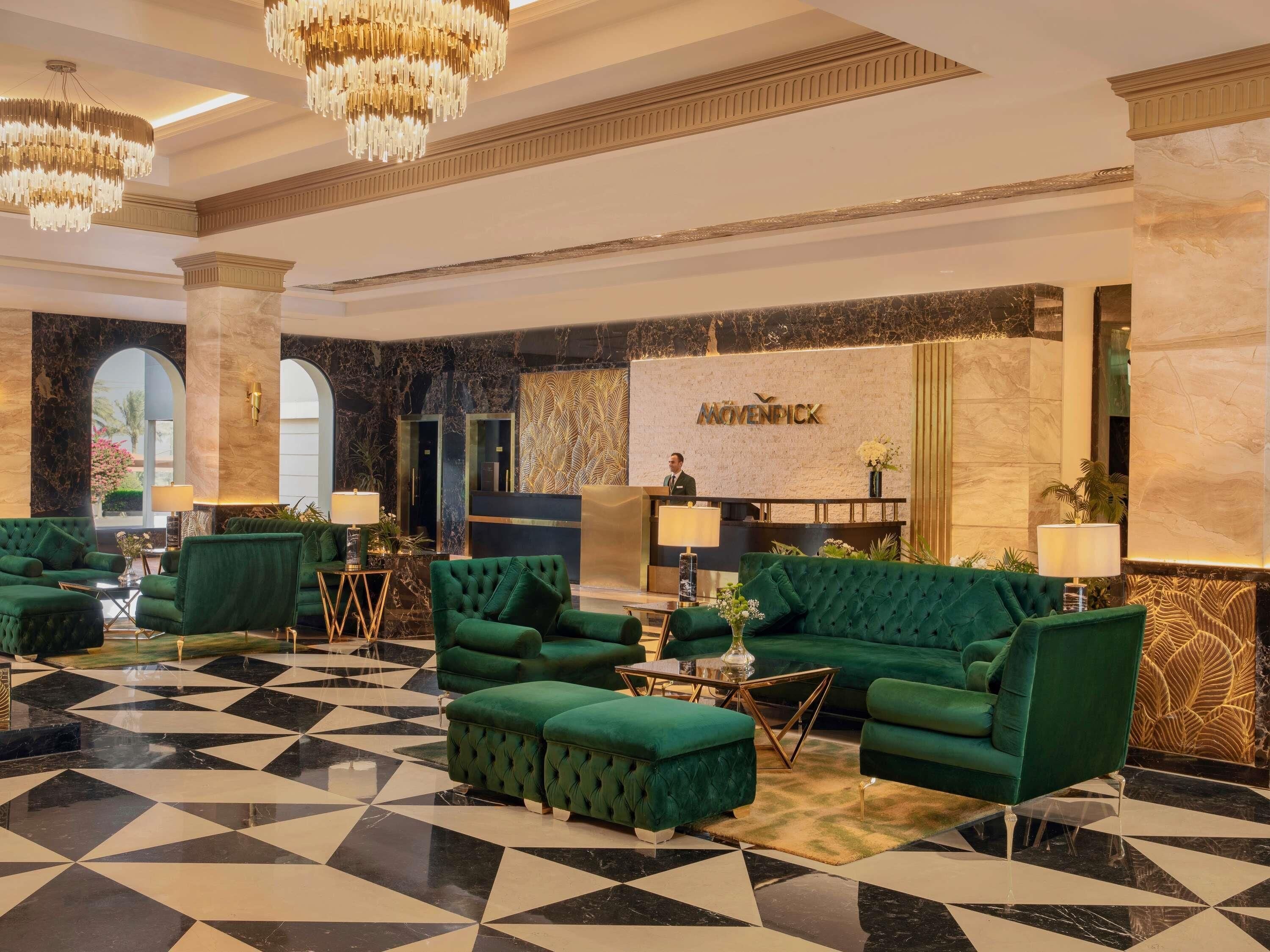 A lobby with green upholstered seating, a reception desk, and a check-in counter.