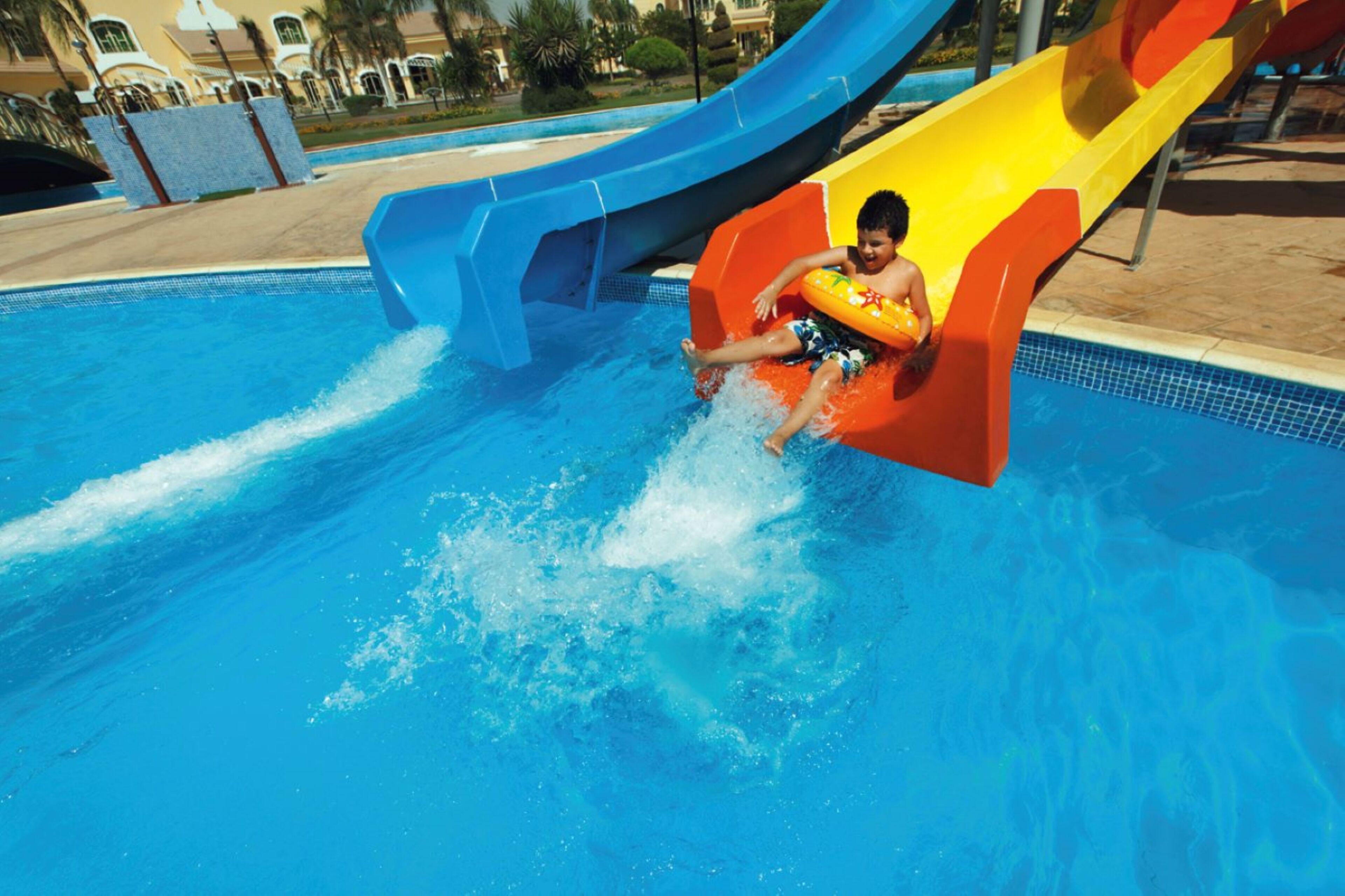 Un enfant glisse le long d’un toboggan aquatique multicolore et atterrit dans une piscine.
