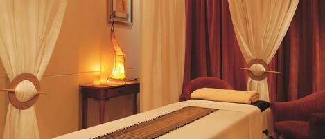 A room with a bed, a table with a lamp, and a chair.