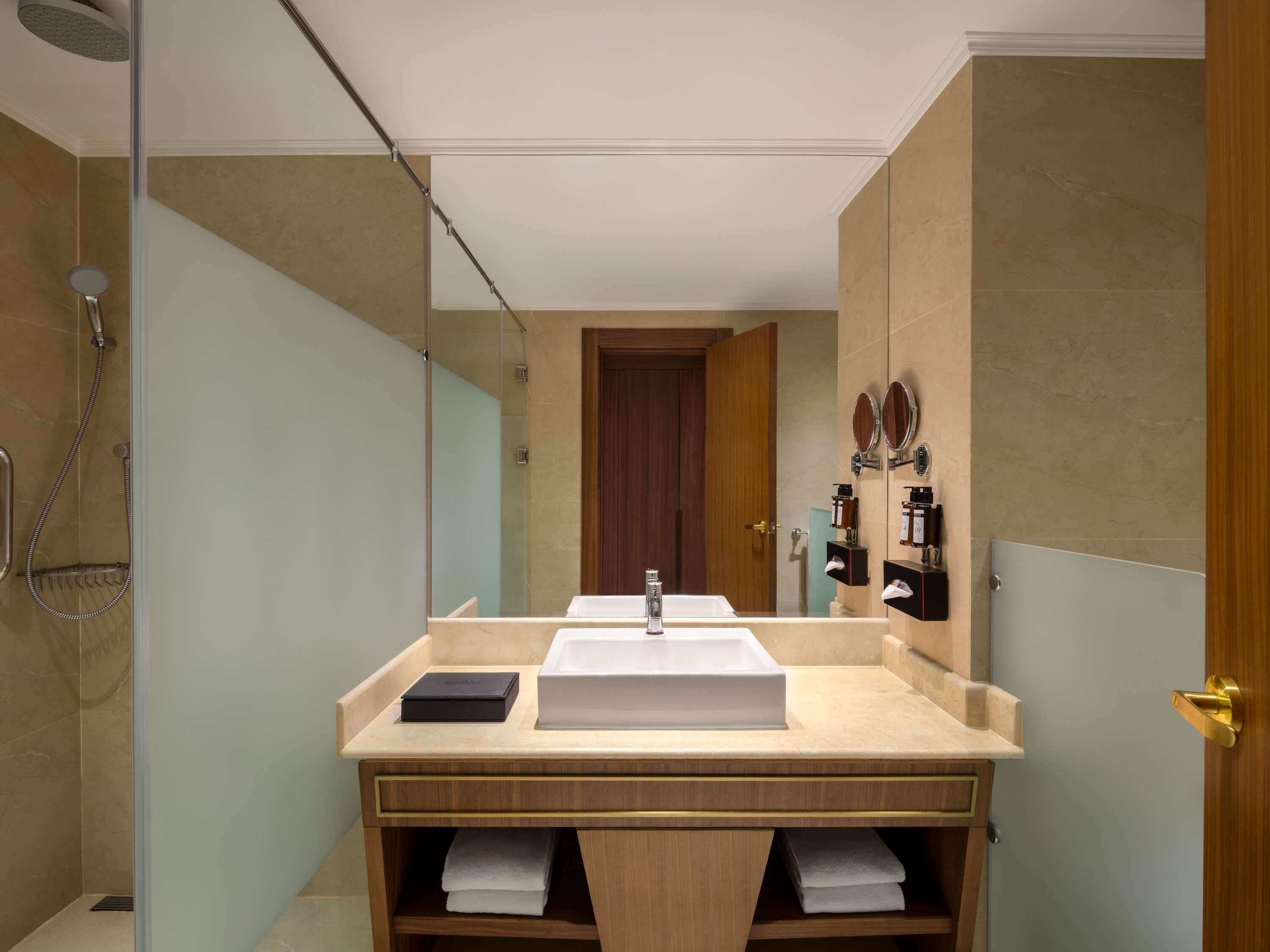 A modern bathroom with a large mirror, a sink, and a shower.