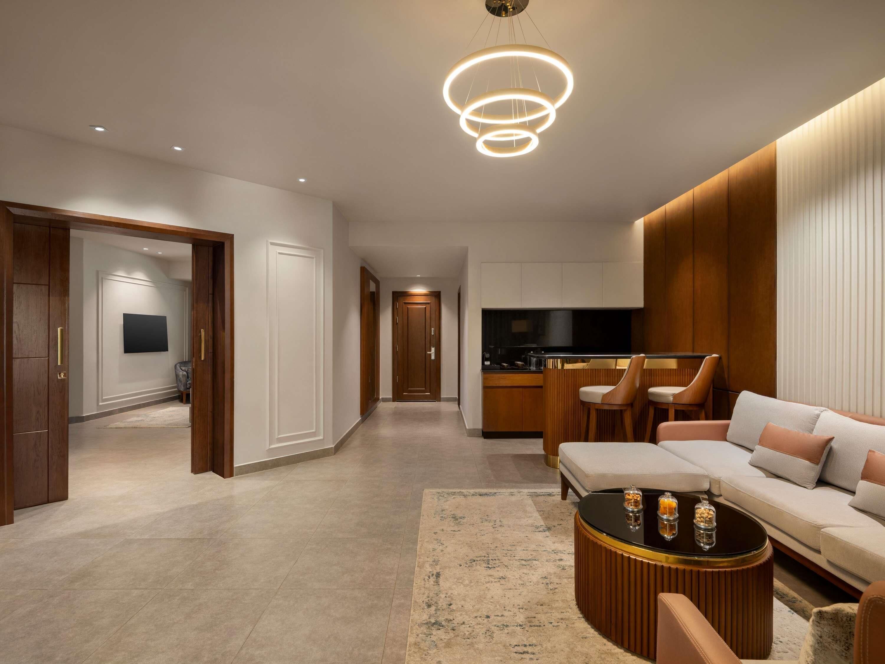 A modern living room with a sofa, coffee table, and a kitchen area in the background.