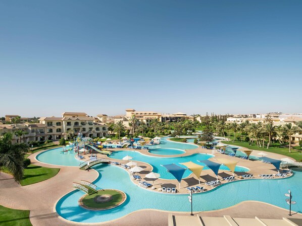 A resort with multiple swimming pools, sun loungers, and palm trees. - Mövenpick Cairo Media City (6th of October City)