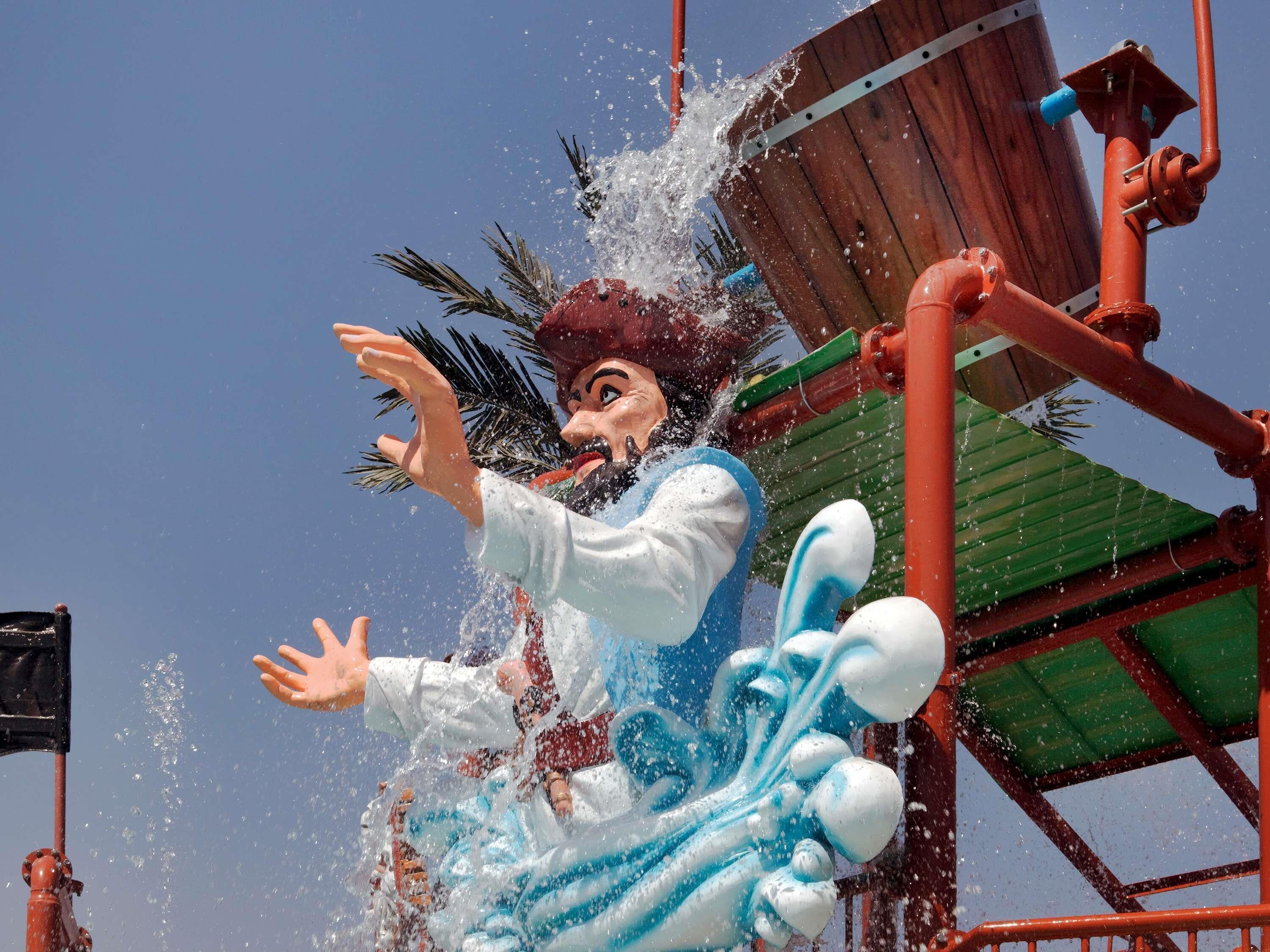 Eine wasserbezogene Attraktion mit einer Figur, die in Wasser versinkt, umgeben von Rohren und einer Holzkonstruktion.