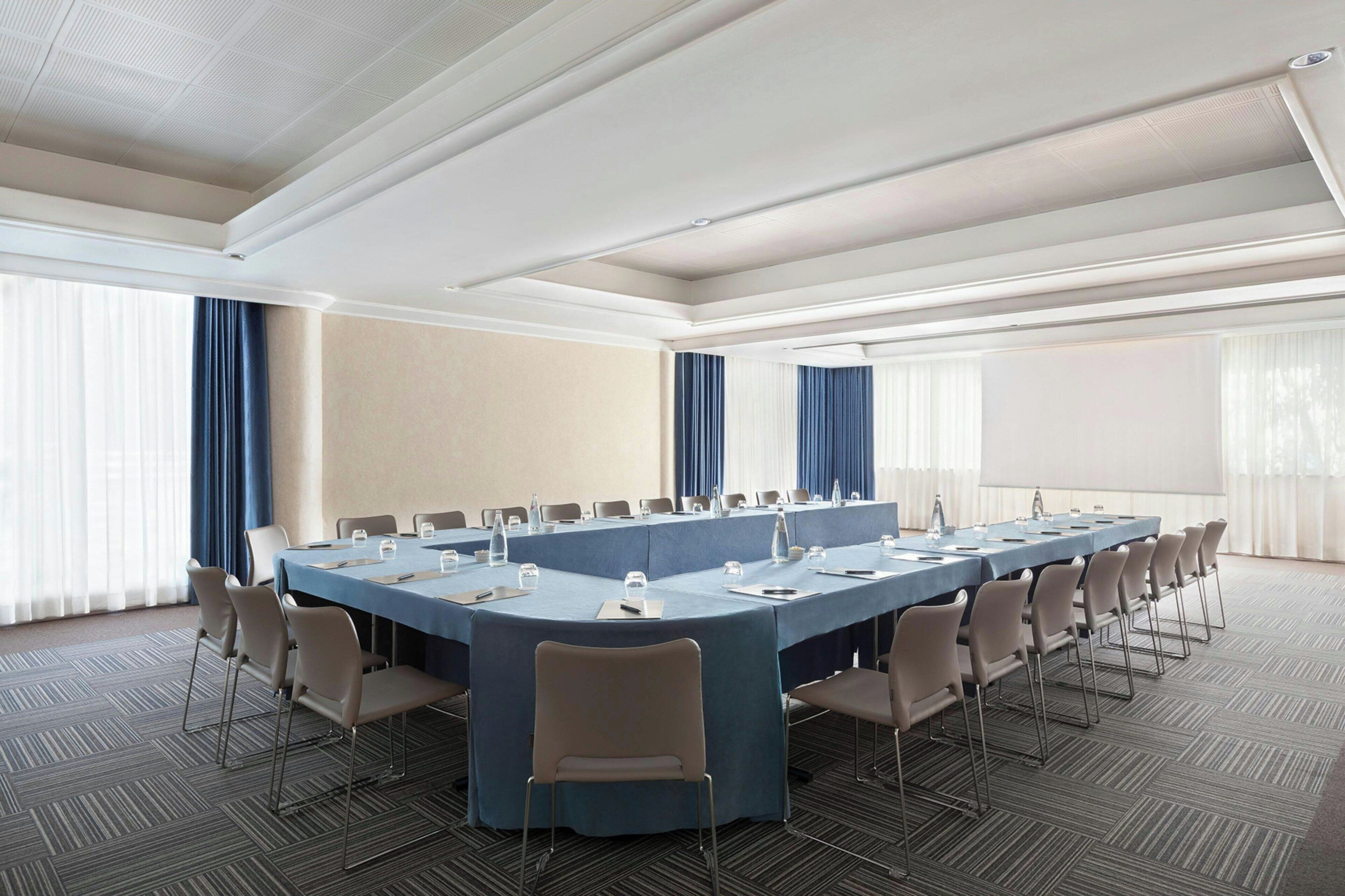 Une salle de conférence équipée d’une longue table, de chaises et d’un écran de projection.