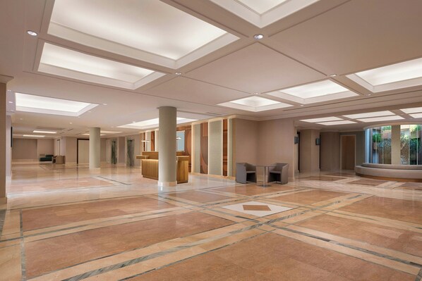 A spacious lobby with a high ceiling, recessed lighting, and a marble floor.