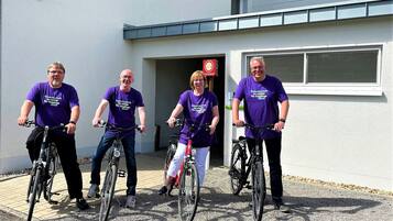 Four people on bicycles in front of a building with a sign that says "Endorsement".