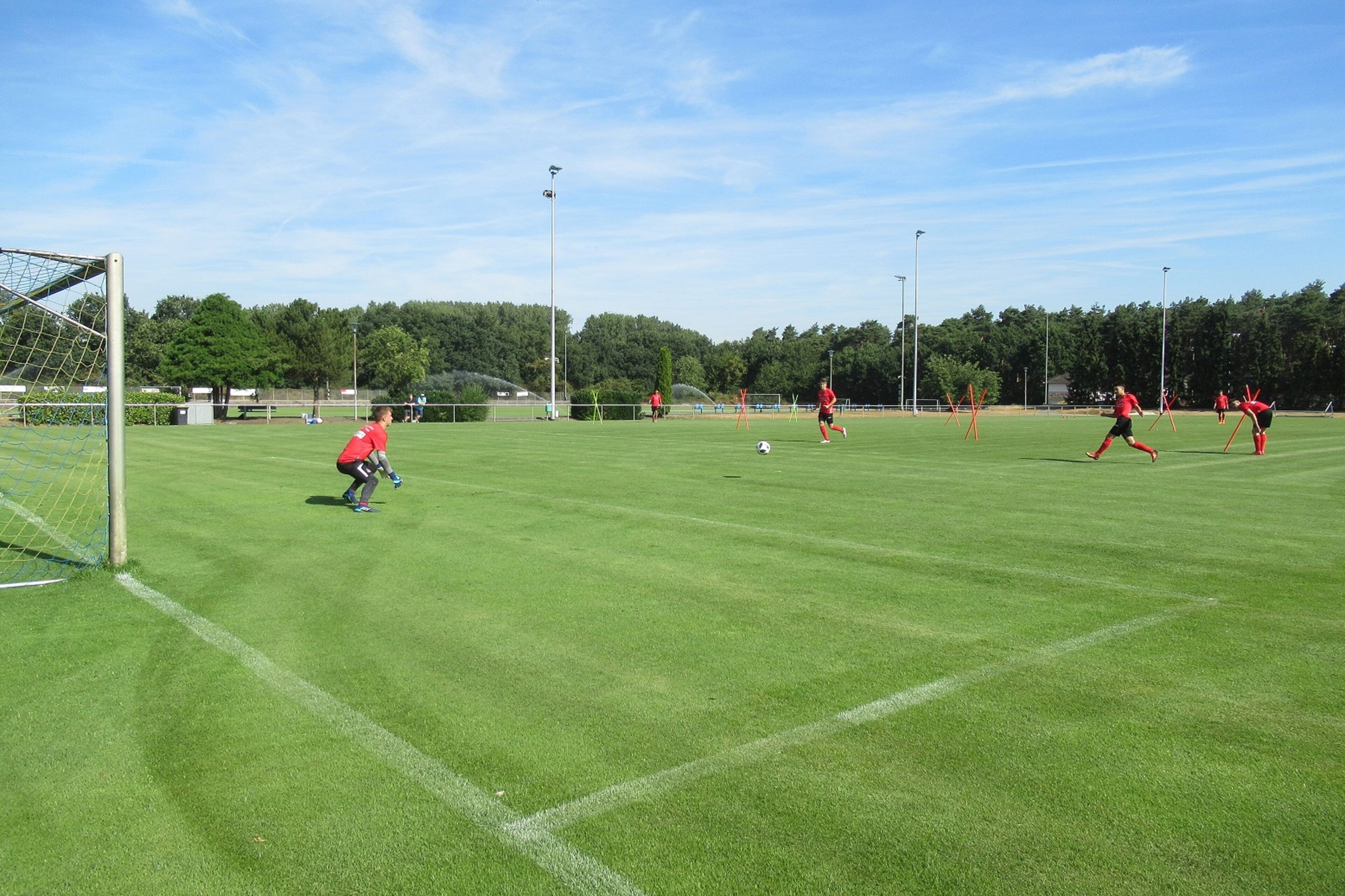 A soccer field with goalposts, players, and a goalkeeper.