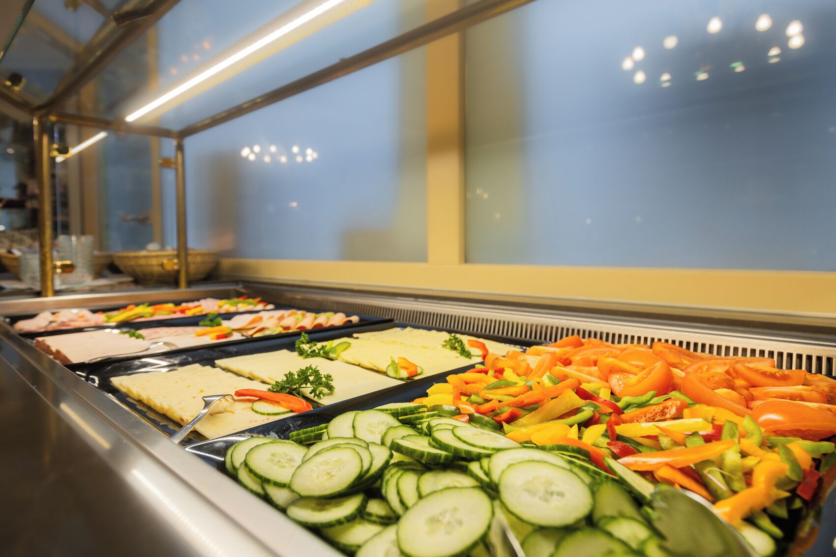 Ein Buffet mit verschiedenen Speisen, darunter Gurkenscheiben, Karotten und weiteres Gemüse.