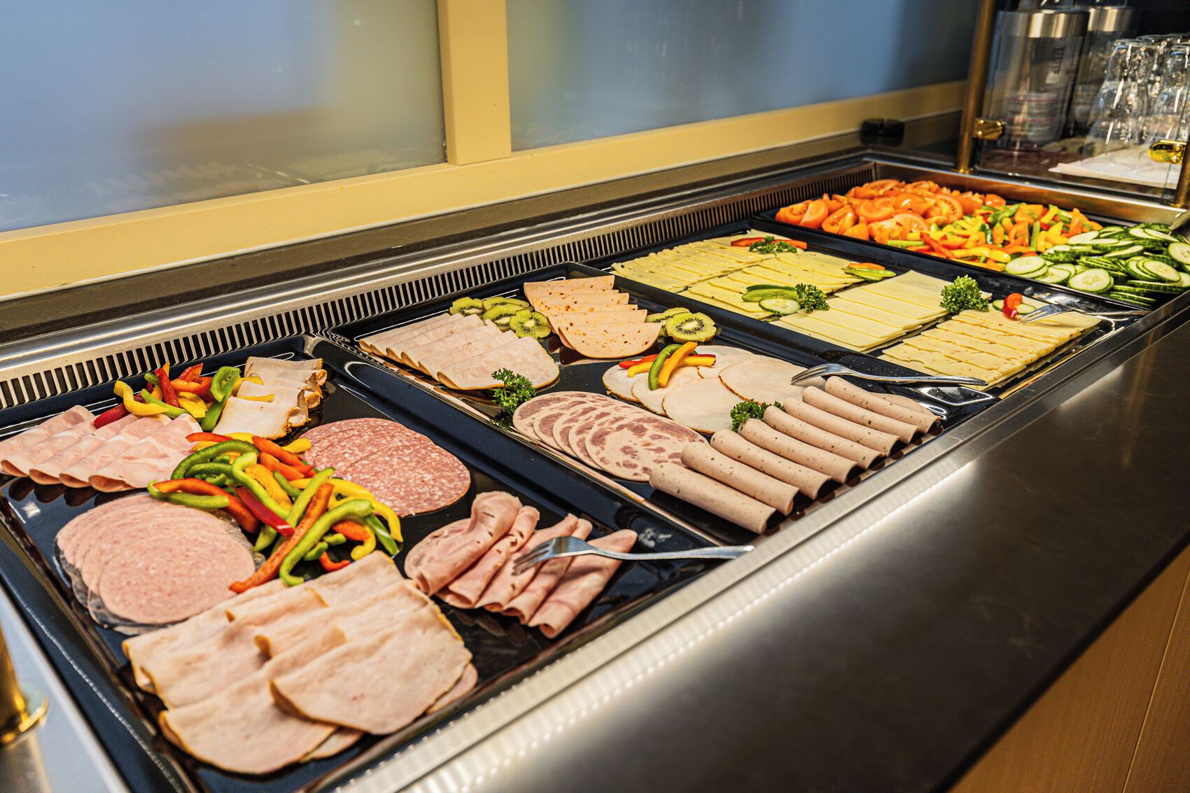 A buffet with various meats, cheeses, and vegetables.