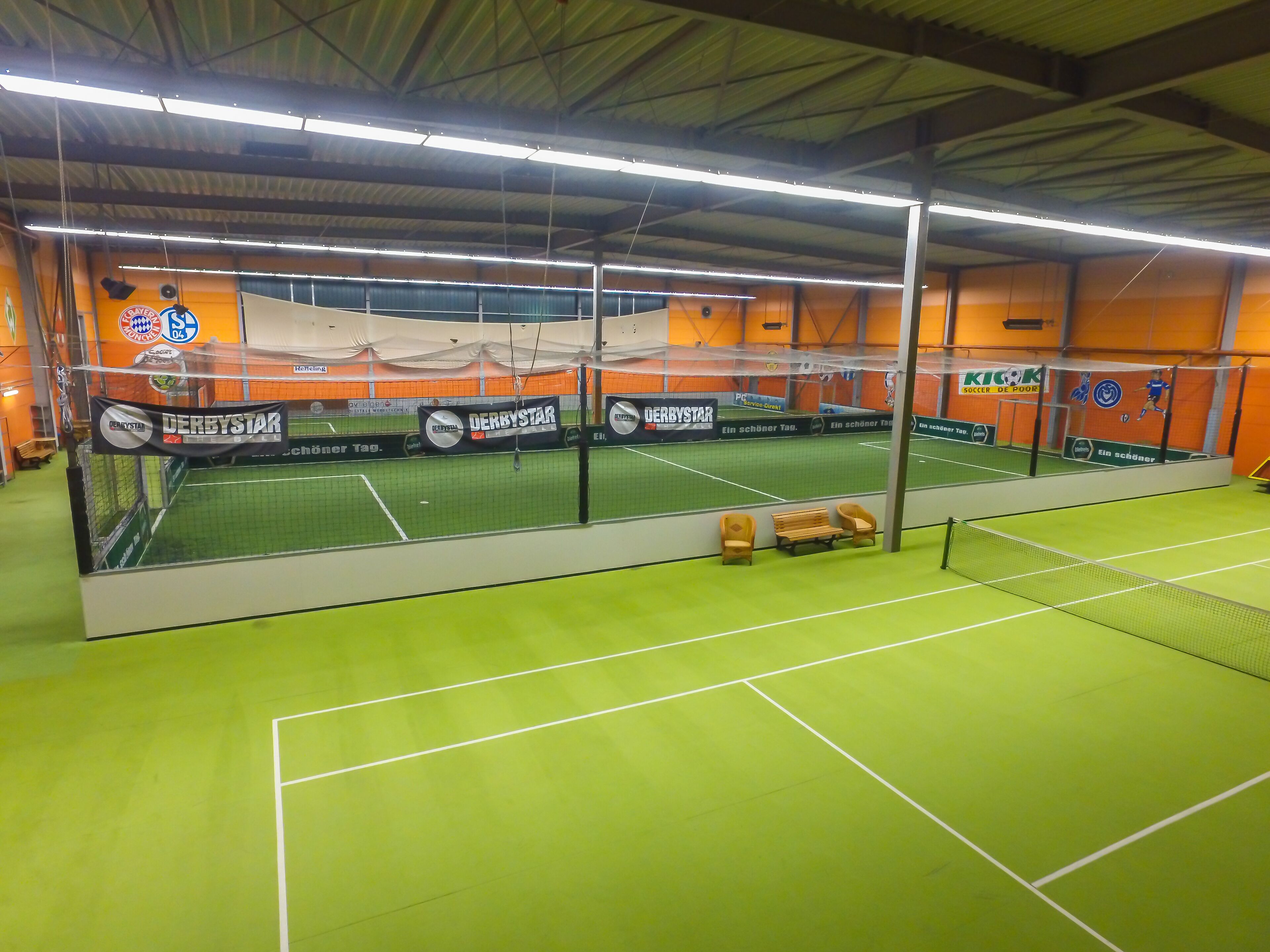 An indoor sports facility with multiple courts, including a tennis court and a soccer field.