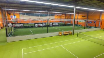 An indoor sports facility with multiple courts, including a tennis court and a soccer field.