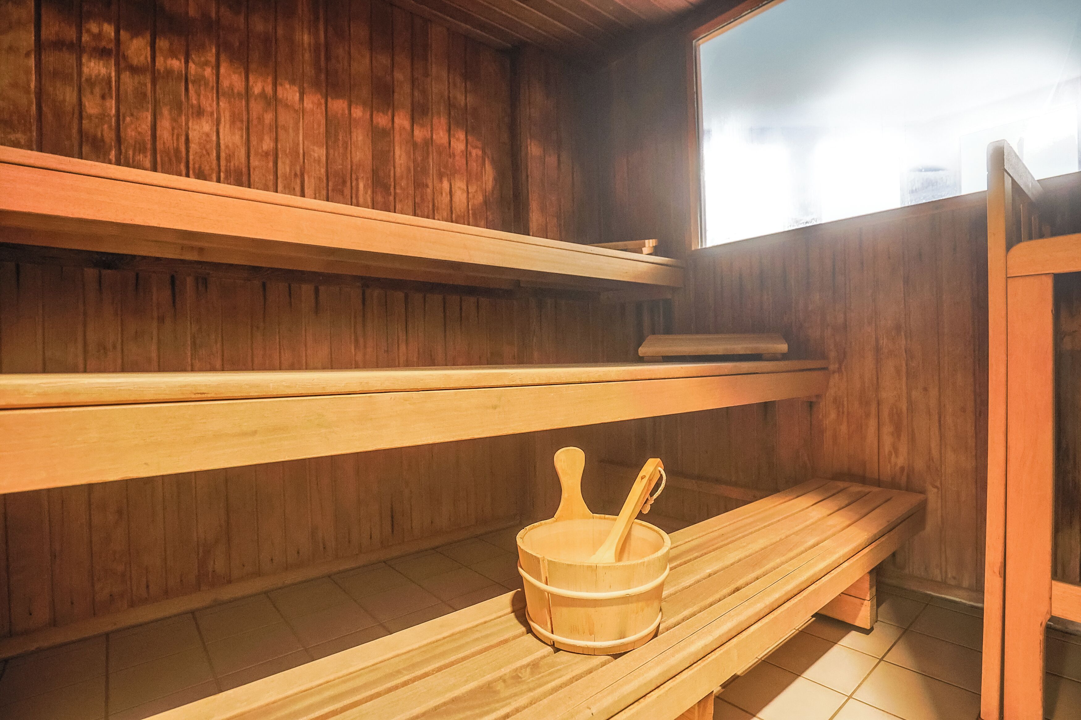 A sauna with wooden benches and a wooden bucket with a ladle.