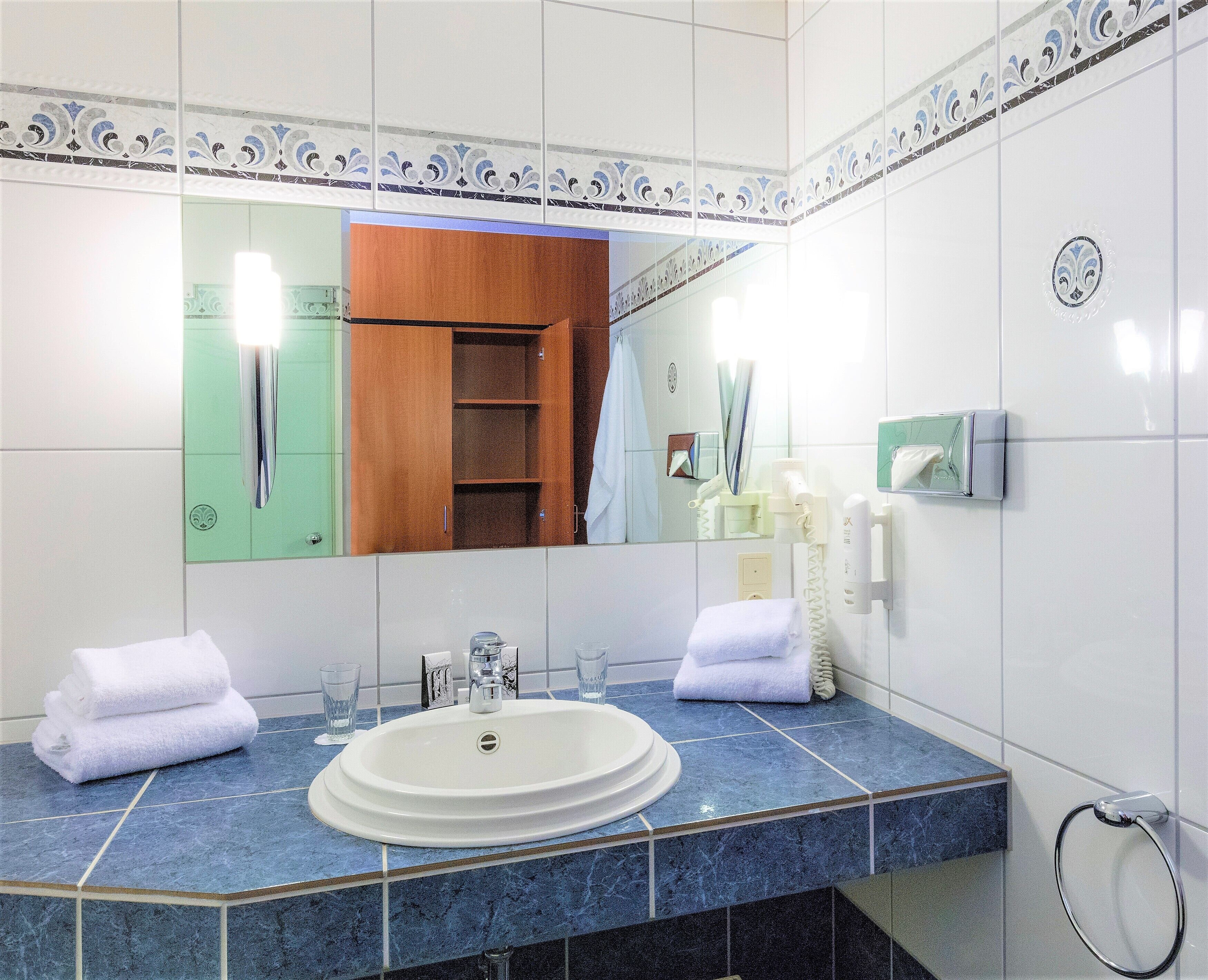 A bathroom with a double sink, a mirror, a towel rack, and a shower area.