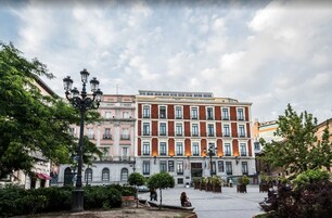 A historic building with a central courtyard, featuring a statue, benches, and a fountain.