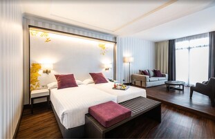 A hotel room with two beds, a sofa, a coffee table, and a chair.