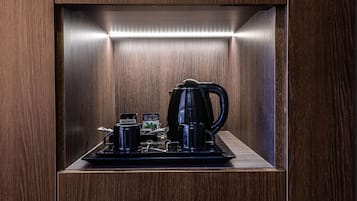 Une pièce compacte et bien éclairée, avec un décor de panneaux en bois, comprenant un coin café équipé d’une bouilloire, de tasses et d’un petit plateau.