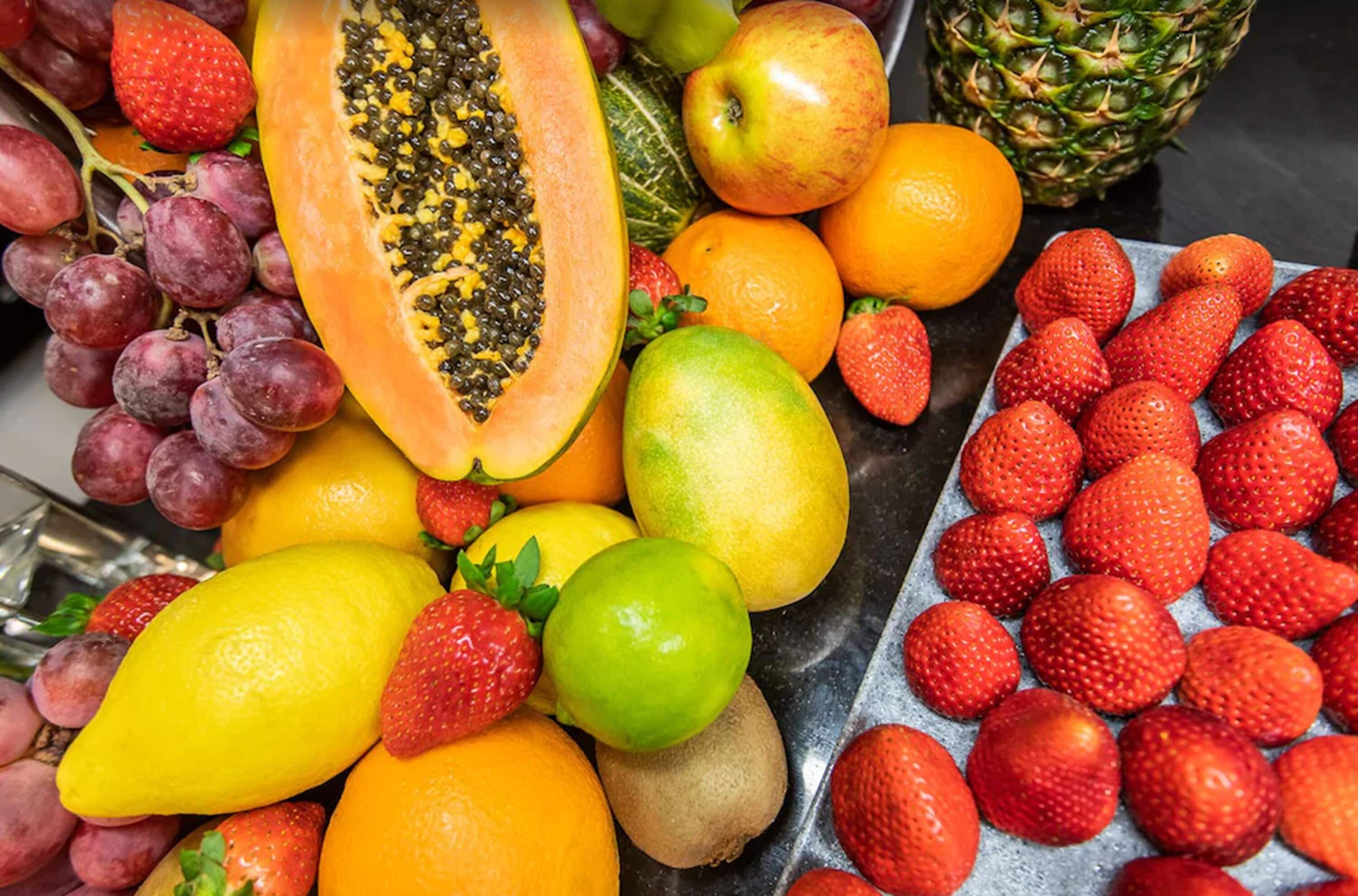 A variety of fresh fruits including grapes, strawberries, oranges, and a pineapple.