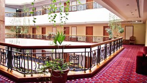Et hotel lobby med et centralt atrium, flere balkoner og potteplanter.
