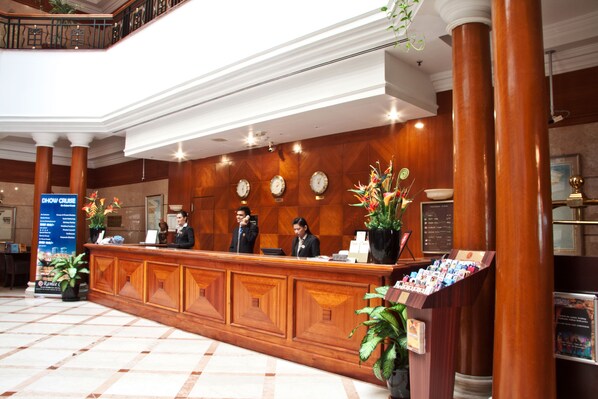 A reception desk with three staff members, a clock, and a menu board.