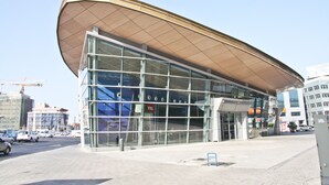 En moderne bygning med en stor glasfacade og et karakteristisk buet tag.