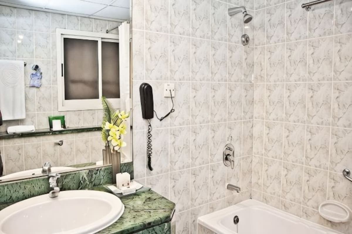 A bathroom with a marble sink, a mirror, a shower, and a toilet.