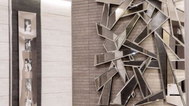 Un interior moderno con una obra de arte metálica geométrica y una exposición vertical de fotografías.