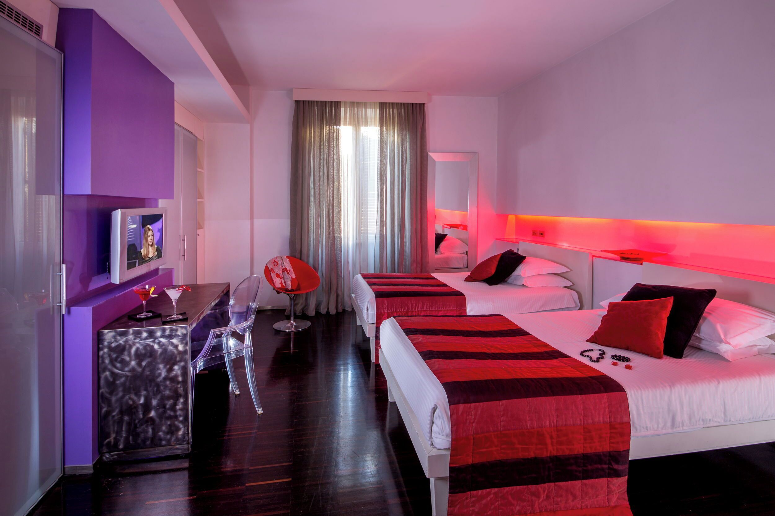 A hotel room with two beds, a small desk, and a chair.