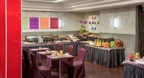 A buffet setup with multiple tables and chairs, arranged in a spacious room with a marble wall and a large window. - Hotel Ariston (Rome)