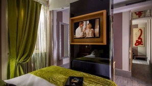 Habitación de hotel con cama, televisor montado en la pared y un cuadro colgado sobre la cama.