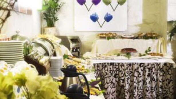 A dining area with a long table set for a meal, a decorative wall piece above, and a potted plant to the side. - Hotel Ariston (Rome)