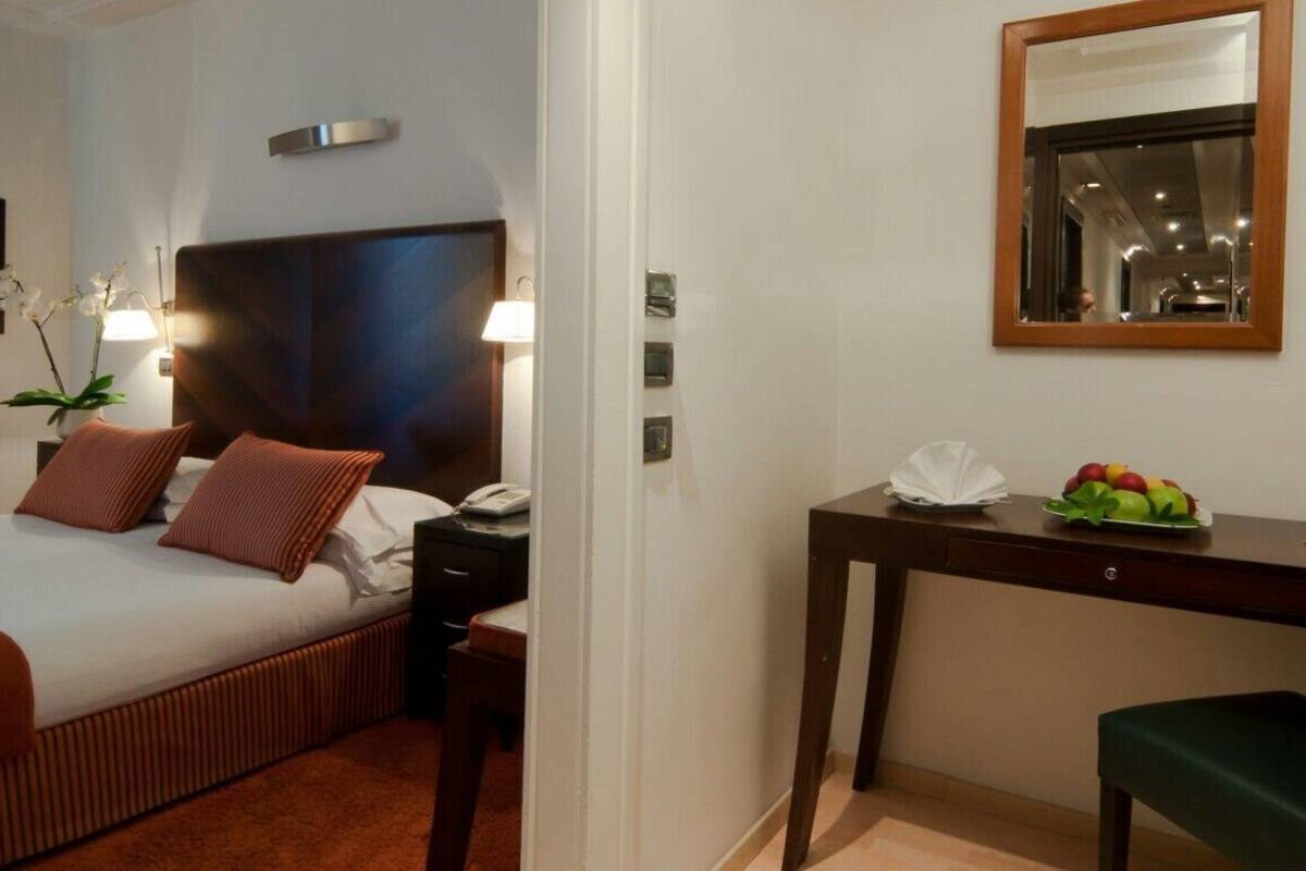 Ein Hotelzimmer mit Bett, Nachttisch, Schreibtisch, Stuhl und Spiegel.