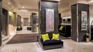 Un moderno vestíbulo con una zona de estar central, un mostrador de recepción y una gran obra de arte abstracta en la pared.