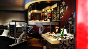 Un área de bar moderna con una barra curva, taburetes y una variedad de botellas y vasos.