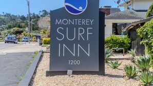 A sign for Monterey Surf Inn, featuring a logo with a wave and a person surfing, and the address 1200. - Monterey Surf Inn (Monterey)