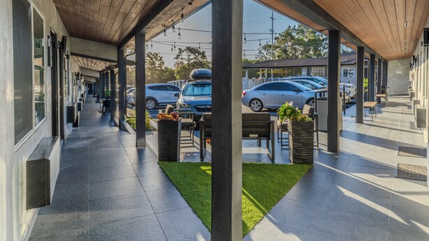 A covered outdoor area with a tiled floor, wooden ceiling, and seating arrangements. - Monterey Surf Inn (Monterey)