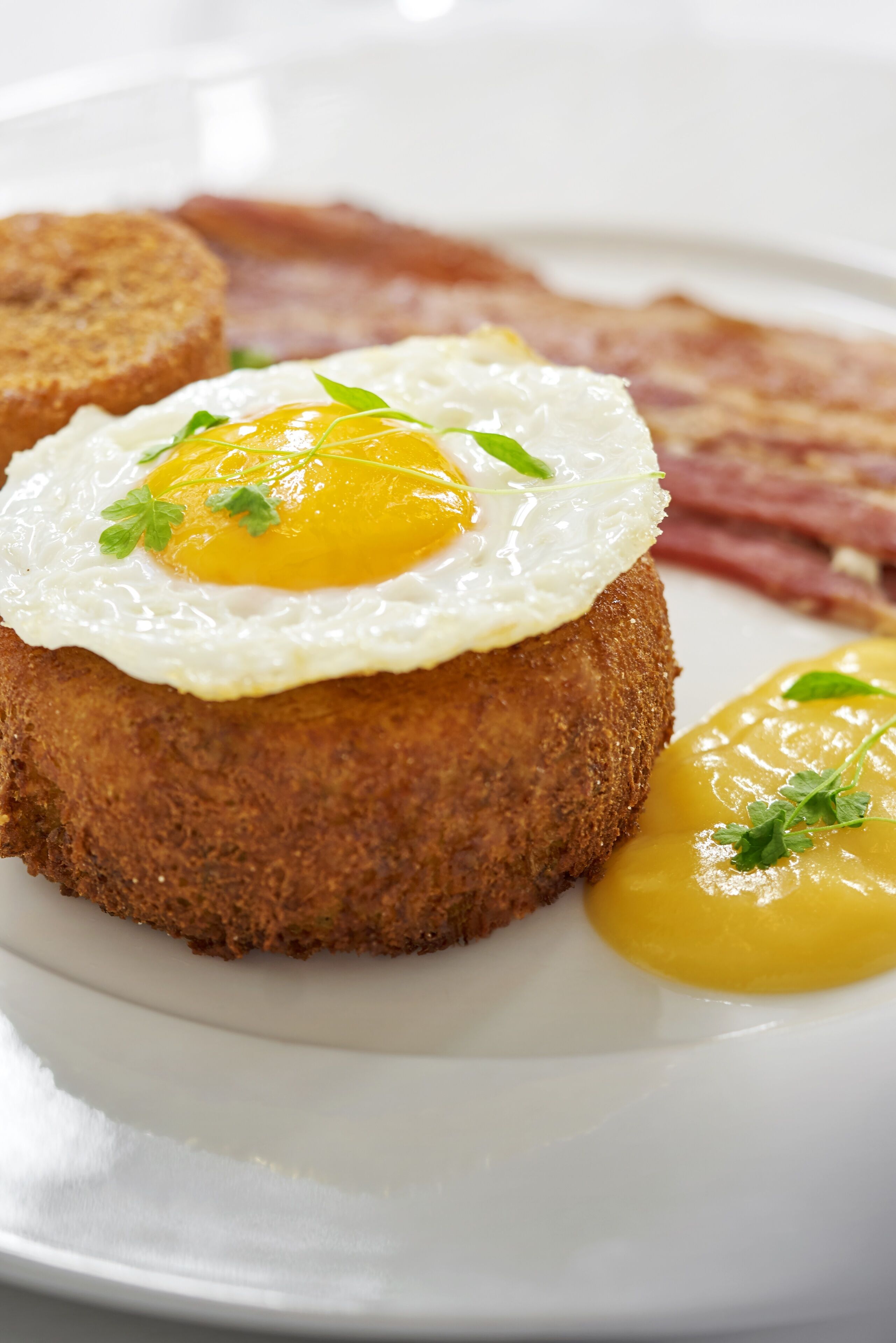 A breakfast plate with a fried egg, toast, and bacon.