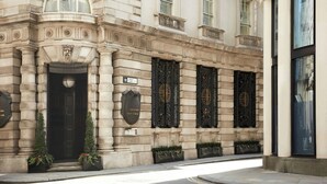Un edificio histórico con una entrada imponente, puertas de hierro ornamentadas y una fachada bien conservada.