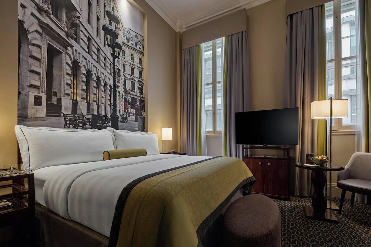 Een hotelkamer met een groot bed, een televisie, een bureau met een lamp en een stoel.