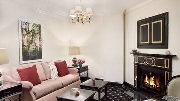A living room with a sofa, coffee table, fireplace, and a chandelier.