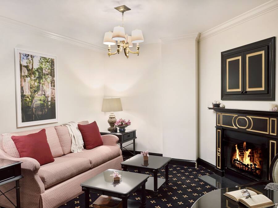 A living room with a sofa, coffee table, fireplace, and a chandelier.