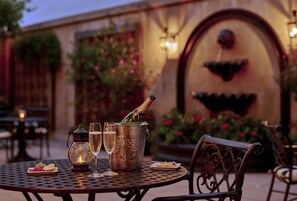 A table set with a bottle of champagne, two glasses, a lantern, and a small plate of fruit. - French Quarter Inn (Charleston)