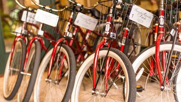 Uma fileira de bicicletas vermelhas, com pneus brancos, cada uma com uma placa numerada indicando a sua posição.
