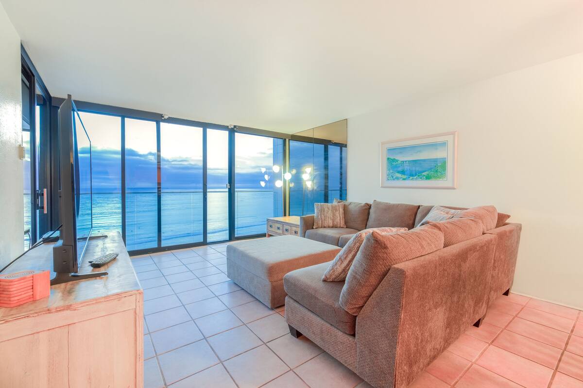 Un amplio salón con un gran ventanal con vistas panorámicas, un sofá cómodo y una mesita con un mando a distancia.