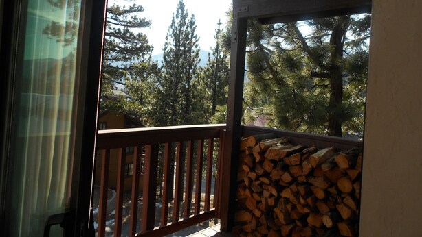 A balcony with a view of trees and a stack of firewood. - Val d'Isere by Mammoth Reservation Bureau (Mammoth Lakes)