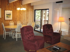 A dining area with a wooden wall, a chandelier, and a view through a sliding glass door. - Val d'Isere by Mammoth Reservation Bureau (Mammoth Lakes)