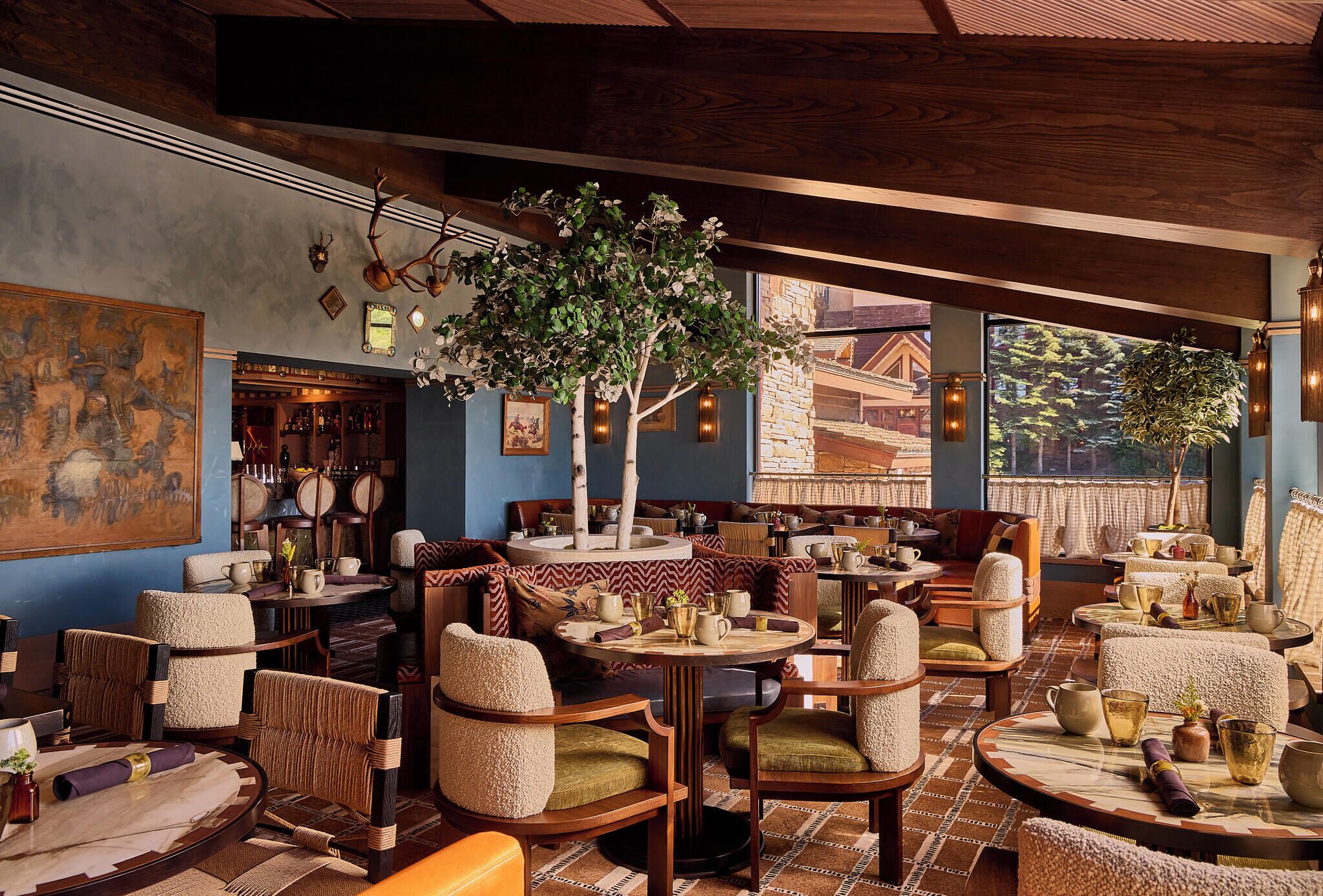 Un restaurante acogedor con muebles de madera, un cuadro grande y vistas a un edificio.